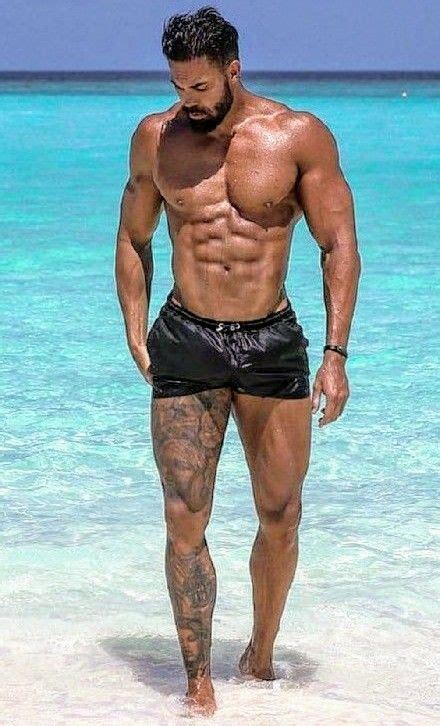 A Man Standing In The Ocean With His Shirt Off And No Shirt On Looking