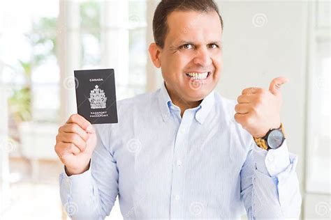 Middle Age Man Holding Holding Canadian Passport Pointing And Showing With Thumb Up To The Side