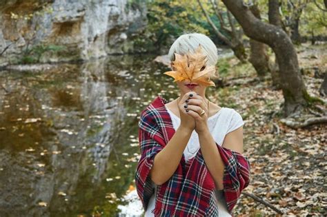 Premium Photo Woman Holding Maple Leaf While Standing By River