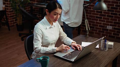 Smiling asian employee writing important emails at computer desk next