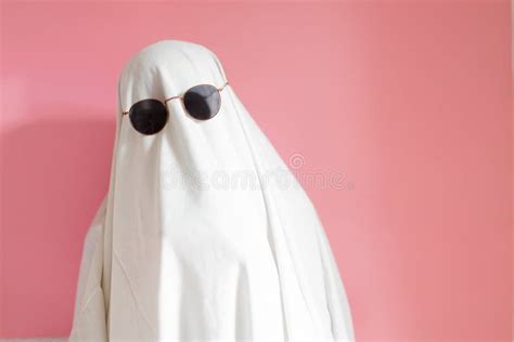 Cute Sheet Costume Ghost With Sunglasses Hugging His Pillow On A Pink Background Halloween