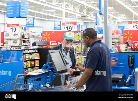 Male African American Cashier Helps Male Anglo Senior Citizen At New