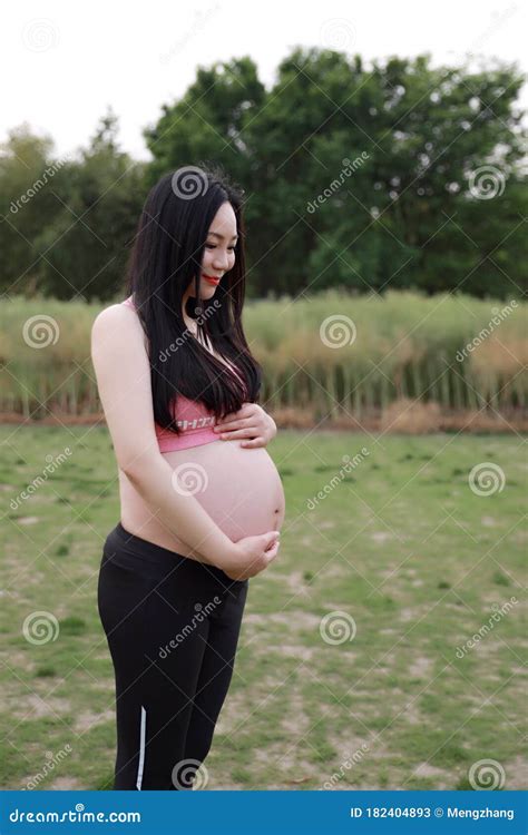 Asian Chinese Pregnant Woman In Yoga Dress In Nature Forest Meditation