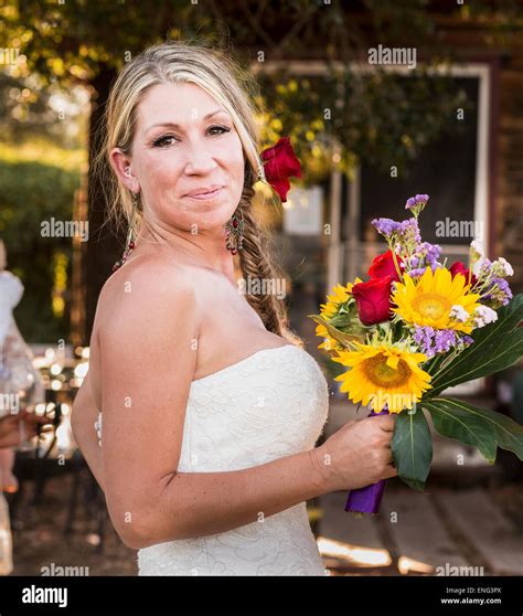 Smiling Caucasian Bride Holding Bouquet Of Flowers Stock Photo Alamy