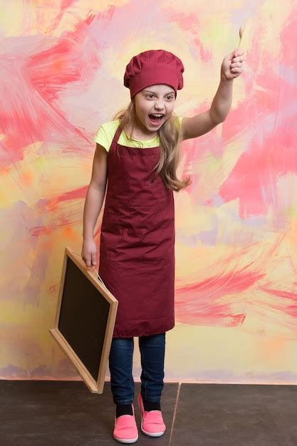 Petite Fille Cuisinier Au Chapeau Avec Tableau Noir Et Cuillère En Bois