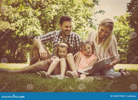 Familia Feliz Con Dos Niños En Prado Usando El Ordenador Portátil Y El