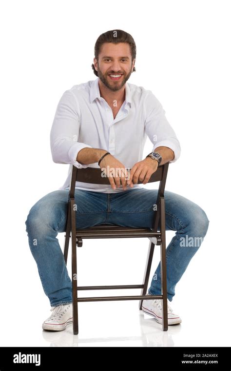 Handsome Man Is Sitting On A Chair Looking At Camera And Smiling