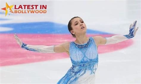 a female figure skating on the ice in a blue and white dress with her ...