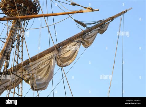 Mast with half-hoisted sail against blue sky Stock Photo - Alamy