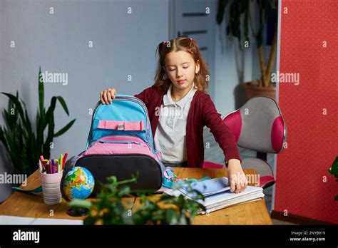 Schoolgirl Put Books And Notes Into Backpack At Home Pupil Prepare