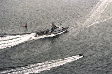 An aerial starboard quarter view of the coastal patrol boat USS CHINOOK (PC-9) rounding the buoy ...