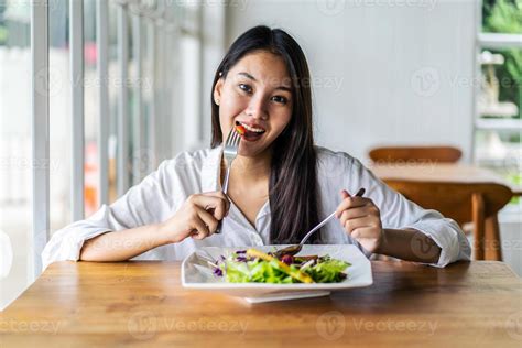 Portrait Of Attractive Asian Smiling Young Woman Eating Salad In