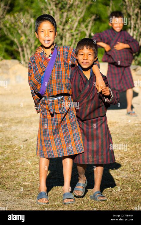 Young Bhutanese Boys Wearing Traditional Striped Gho Robe In Stock