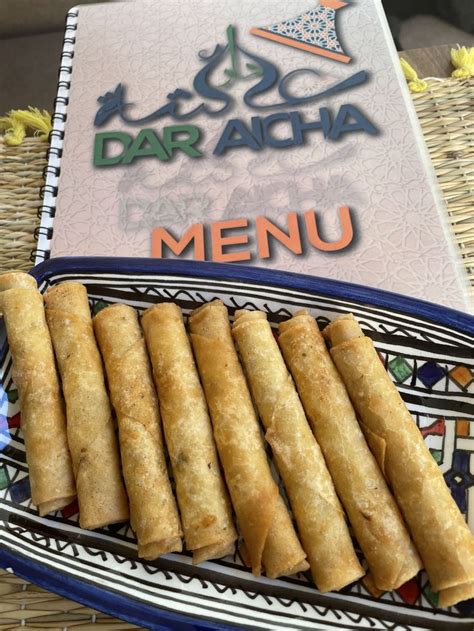 Some Food Is Sitting On A Plate Next To A Menu And A Basket Full Of Rolls