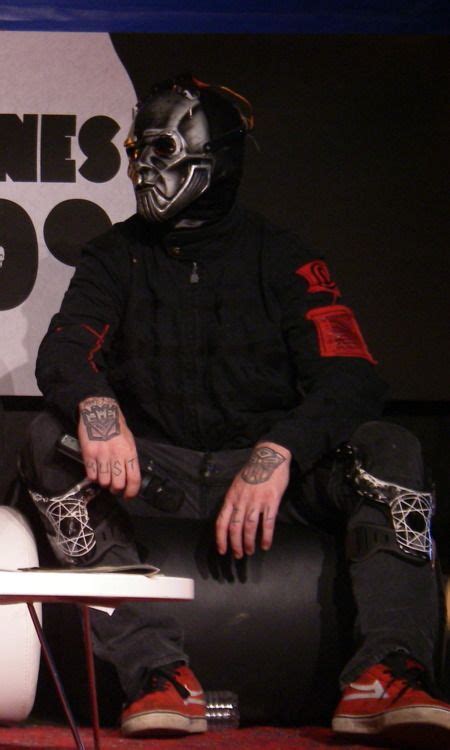 Two Men In Masks Sitting On Top Of A White Table Next To Each Other