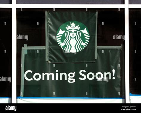 A Sign In A Window Announces That A New Starbucks Coffee Shop Will Open