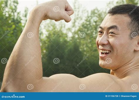 Side View Of Muscular Smiling Man Showing Off And Flexing His Bicep