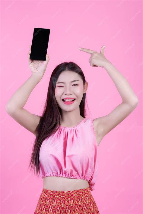 ピンクの背景にスマートフォンを持って美しい女性。 無料の写真