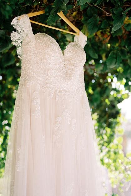 Vestido De Noiva Pendurado Em Um Cabide De Madeira Debaixo De Uma