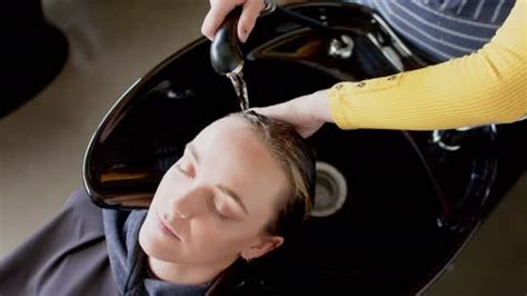 Hands Of Caucasian Female Hairdresser Washing Hair Of Relaxed Female Customer At Hair Salon