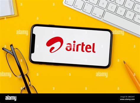 A Smartphone Showing The Bharti Airtel Logo Rests On A Yellow