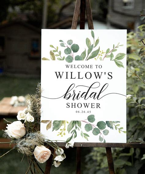 A Welcome Sign For A Bridal Shower With Flowers And Greenery On The Easel