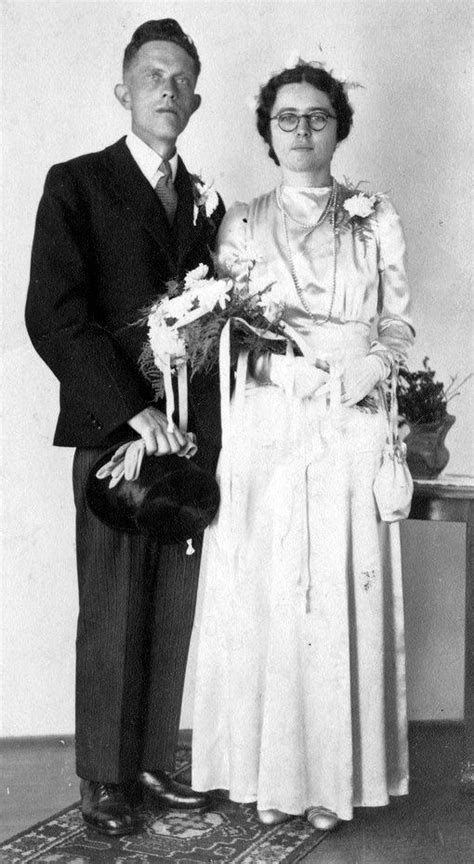 An Old Black And White Photo Of A Man And Woman Standing Next To Each Other