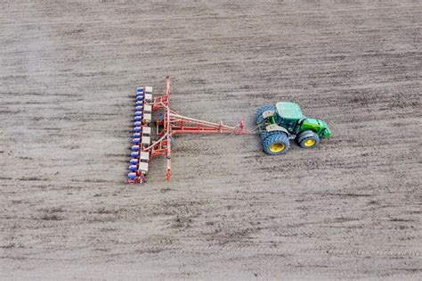 Premium Photo Sowing Of Corn Tractor With A Seeder On The Field Using