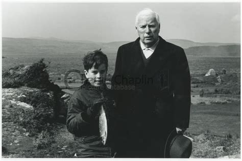 Eugene Chaplin holding a fish next to his father Charles Chaplin, while ...