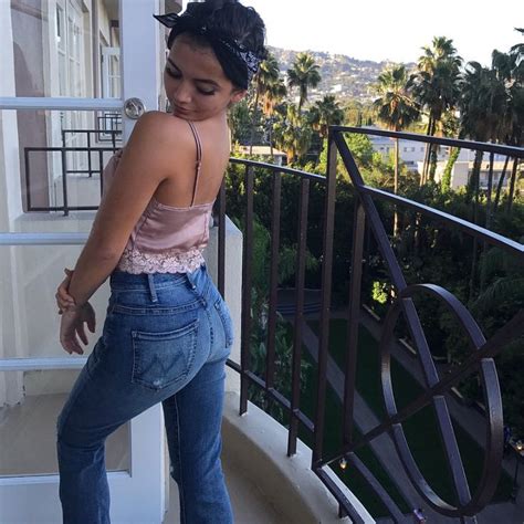 a woman in high waist jeans leaning against a balcony railing and ...