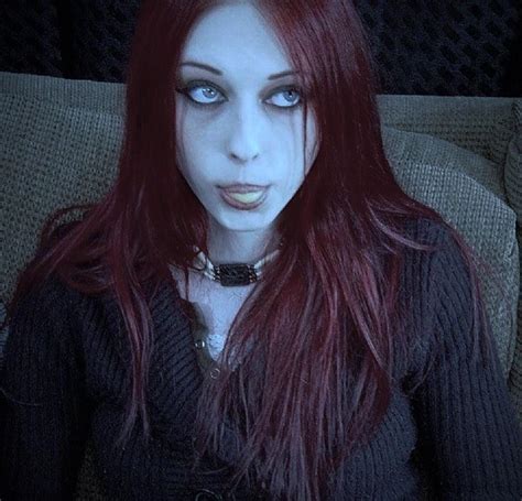 A Woman With Red Hair And Blue Eyes Is Sitting On A Couch Looking At The Camera