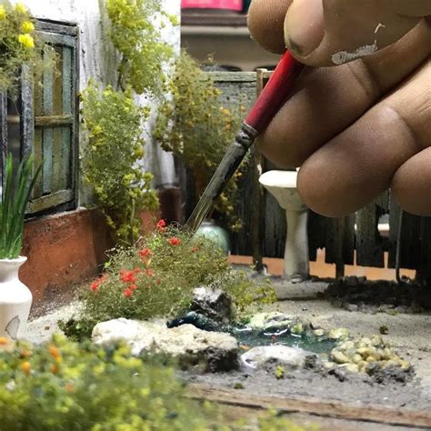 A Hand Holding A Red Pen In Front Of Some Plants And Rocks On The Ground