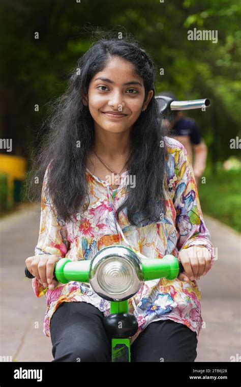 Beautiful Indian Girl Riding Green Color Tricycle Enjoying Summer Vacation In Park Or Garden