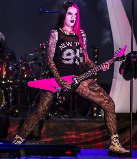 a woman with pink hair and tattoos on her body is holding a guitar in ...