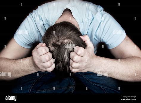 Man Holding His Head In His Hands Sitting On Floor Over Black