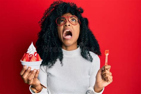 African American Woman With Afro Hair Eating Strawberry Ice Cream Angry And Mad Screaming