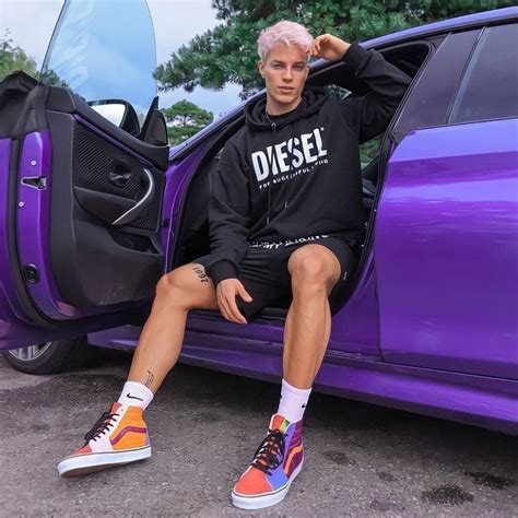 A Man With Pink Hair Sitting On The Door Of A Purple Car Wearing Sneakers