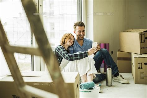 Smiling Couple Having A Break From Renovating[11094037457]の写真素材・イラスト素材｜アマナイメージズ