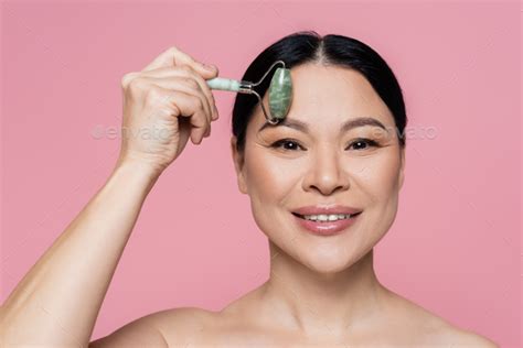 Smiling Asian Woman With Naked Shoulders Massaging Forehead With Jade