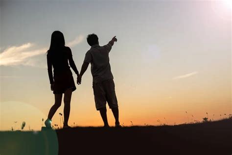 Silhouette Of A Man And Woman Holding Hands With Each Other Walking