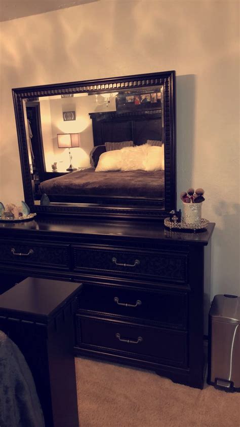 A Bedroom Scene With Focus On The Dresser And Bed In The Mirror Which