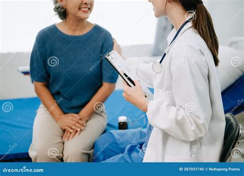 Doctor And Senior Female Patient Who Lie On The Bed While Checking