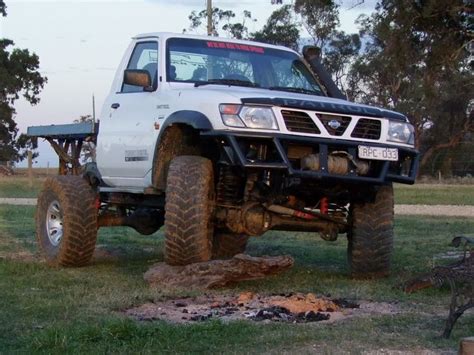 a white truck parked on top of a lush green field next to a fire pit