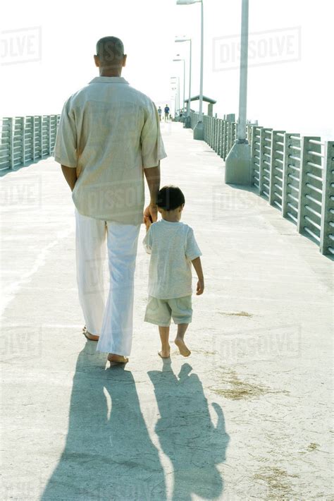 Father And Son Walking Together Holding Hands Rear View Stock Photo