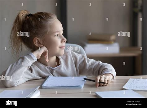 Dreamy Little Girl Distracted From Studying At Home Stock Photo Alamy