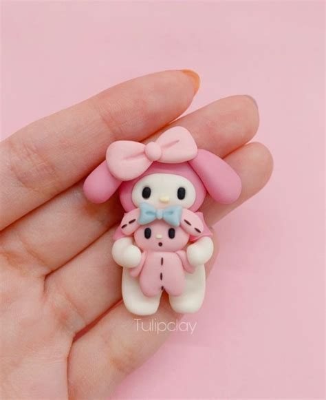 A Hand Holding A Pink And White Hello Kitty Brooch On Its Palm