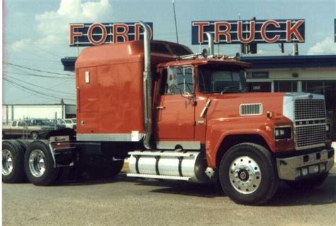 A Red Semi Truck Parked In Front Of A Building With The Word Ford On It