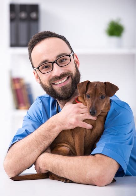 Premium Photo Smiling Male Veterinarian Is Holding A Dog