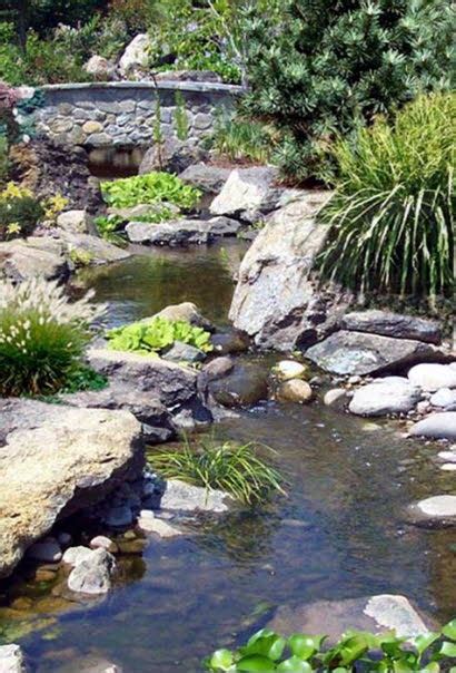 A Small Pond Surrounded By Rocks And Plants