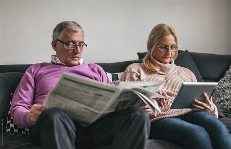 Woman Browsing Online And Man Reading Newspaper By Stocksy